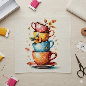 May include: Cross-stitch design of a stack of colourful teacups with floral accents. The cups are in shades of red, yellow, blue, and orange, with a saucer at the bottom. The design includes leaves and flowers, with spools of thread and scissors nearby.
