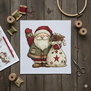 May include: A finished cross-stitch of Father Christmas in a red hat and coat, waving with a sack of gifts. The design is on white fabric, surrounded by spools of thread, a needle, scissors, and an embroidery hoop. The background is a wooden surface.