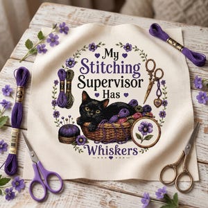 Op de afbeelding: Een vierkant stuk gebroken wit Aida-stof met een kruissteekpatroon van een zwarte kat in een mand met de tekst My Stitching Supervisor Has Whiskers, omringd door paarse bloemen, borduurschaar en een speldenkussen.