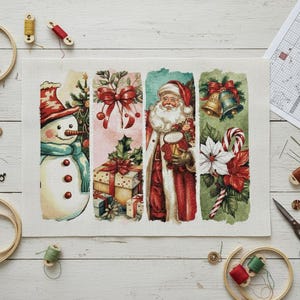 Può includere: Un disegno natalizio a punto croce con un pupazzo di neve, regali, Babbo Natale, campane e bastoncini di zucchero. L'opera è su tela bianca, circondata da telai da ricamo, rocchetti di filo e un foglio modello.
