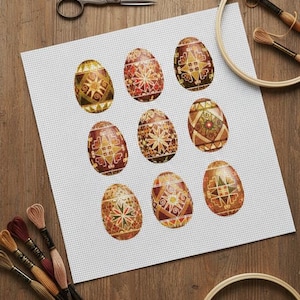 Puede incluir: Un proyecto de punto de cruz con nueve huevos de Pascua decorados. Los huevos muestran varios patrones geométricos y florales en tonos dorados, rojos y marrones. Hilo de bordar, tijeras y un bastidor están dispuestos alrededor del proyecto sobre una superficie de madera.