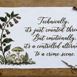 May include: A white cross-stitch project with the text "Technically, it's just counted thread. But emotionally, it's a controlled alternative to a crime scene." Features botanical illustrations and embroidery floss. Includes scissors and a needle minder.