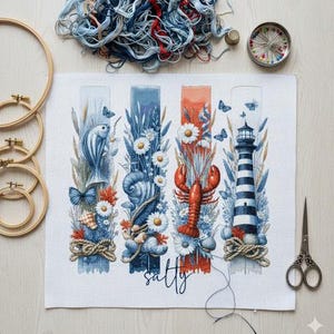May include: A cross-stitch project with a nautical theme, featuring a fish, seashell, lobster, and lighthouse design. The word "salty" is written in cursive. Embroidery hoops, scissors, and thread are also visible.