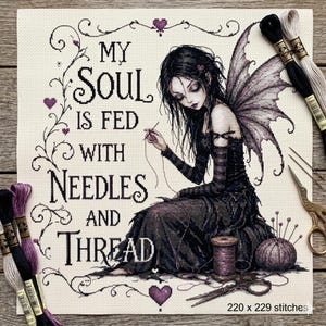 Könnte beinhalten: Ein Kreuzstichmuster auf cremefarbenem Stoff mit einer dunkelhaarigen Fee in einem schwarzen Kleid mit Flügeln. Der Text lautet "MY SOUL IS FED WITH NEEDLES AND THREAD". Um die Figur herum liegen Stickgarn, Nadeln, eine Schere und eine Garnrolle.