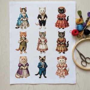 以下が含まれることがあります： ヴィンテージの服を着た9匹の擬人化された猫のクロスステッチパターン。猫はドレス、スーツ、セーラー服など、さまざまな衣装を着ています。刺繍糸、フープ、ハサミが背景にあります。