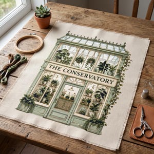 Könnte beinhalten: Ein Kreuzstich-Stickprojekt auf beigem Stoff, das ein detailliertes grünes Gewächshaus mit Glasscheiben, verschiedenen Topfpflanzen und dem Text THE CONSERVATORY zeigt. Das Design umfasst Kletterpflanzen und architektonische Details.