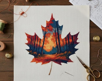 May include: A cross-stitch project featuring a colorful autumn leaf design. The leaf is filled with a forest scene in shades of orange, red, and blue. The project is on white fabric, with spools of thread, scissors, and thimbles on a wooden surface.