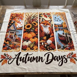 Può includere: Un pannello in tessuto bianco con un motivo a punto croce diviso in quattro sezioni verticali raffiguranti una casa, zucche, una volpe e un lago. Il testo "Autumn Days" è stampato in basso. Un metro a nastro indica 71 cm.