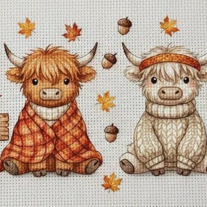 Op de afbeelding: Een kruissteekontwerp met vier Schotse Hooglanders in herfstkleding. Eén draagt een pompoenhoodie, een ander een geruite sjaal, een derde een trui en de laatste een heksenhoed. Het bordje luidt "Happy Fall". Eikels en bladeren zijn verspreid.