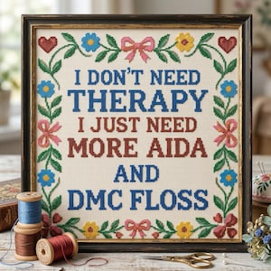 Może przedstawiać: Oprawiona haftem krzyżykowym z napisem "I DON'T NEED THERAPY I JUST NEED MORE AIDA AND DMC FLOSS". Dzieło otoczone jest kwiatową bordiurą z sercami, kokardkami i kwiatami. Szpule nici i nożyczki na pierwszym planie.
