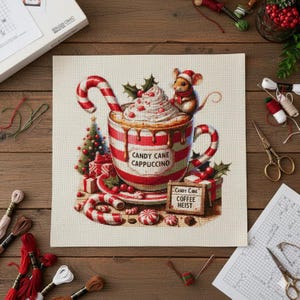 Puede incluir: Diseño de punto de cruz que presenta una taza a rayas rojas y blancas de "Candy Cane Cappuccino" con un bastón de caramelo, crema batida y un ratón con un gorro de Papá Noel. También se incluye un pequeño árbol de Navidad y regalos.