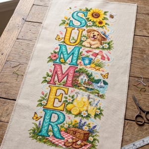 May include: A rectangular beige fabric piece featuring a vertical cross-stitch design spelling SUMMER. Each letter incorporates seasonal imagery including a puppy, a beach scene, a cottage, lemons, and a picnic basket, surrounded by flowers and butterflies.