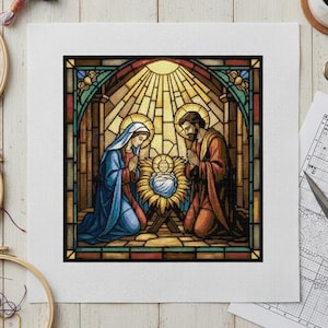 May include: A cross-stitch design depicting the Nativity scene in a stained-glass style. The image features Mary and Joseph kneeling beside the baby Jesus in a manger, with a radiant sunburst background. The color palette includes blues, reds, and golds.