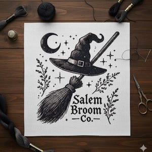 以下が含まれることがあります： 黒と白の魔女をテーマにした刺繍アート。魔女の帽子、ほうき、三日月、星が描かれています。「Salem Broom Co.」の文字がほうきの下に表示されています。白い布に描かれたアートワークです。