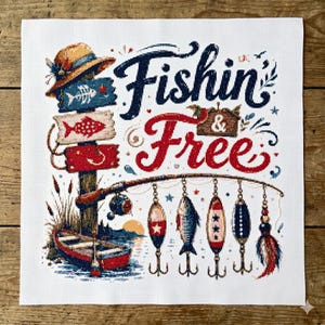 May include: A needlepoint canvas featuring a fishing theme. The design includes a sign with fish illustrations, a fishing rod with lures, a boat, and the words "Fishin' & Free" in navy and red. A straw hat sits atop the sign.