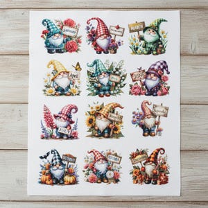 Op de afbeelding: Een stoffen paneel met twaalf kabouters, elk een maand van het jaar vertegenwoordigend. De kabouters worden afgebeeld met verschillende hoeden, houden borden met maandnamen vast en zijn omringd door seizoensgebonden bloemen en bladeren. Het kunstwerk is kleurrijk en gedetailleerd.