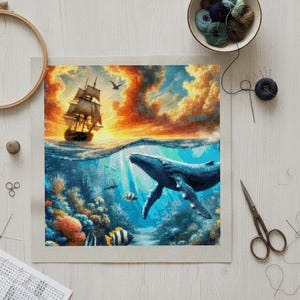 Könnte beinhalten: Kreuzstichprojekt mit einer lebendigen Ozeanszene. Ein großer blauer Wal schwimmt unter der Oberfläche, mit einem Segelboot am Horizont unter einem Sonnenuntergangshimmel. Das Projekt befindet sich auf einer weißen Leinwand, umgeben von Stickzubehör.