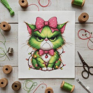 May include: Cross-stitch art of a grumpy green cat with a pink bow and bow tie, wrapped in Christmas lights. The cat has an angry expression. The artwork is surrounded by sewing supplies, including spools of thread and scissors.