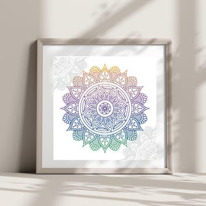 Könnte beinhalten: Ein gerahmter Druck eines farbenfrohen Mandala-Designs mit einem Regenbogen-Verlauf. Das Mandala ist von einem weißen Hintergrund und einem silbernen Rahmen umgeben.