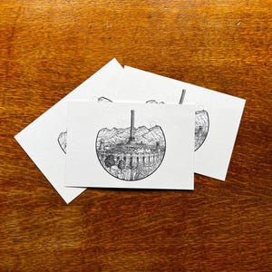May include: Three black and white ink drawings of a city skyline with a tall tower in the center. The drawings are on white card stock.