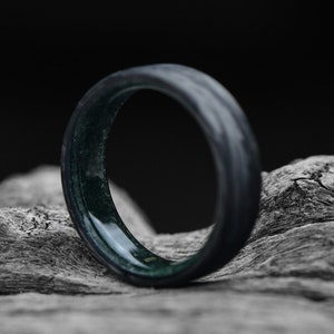 以下が含まれることがあります： 黒と緑のリングで、縁が斜めにカットされています。リングは耐久性のある素材で作られており、洗練されたモダンなデザインです。