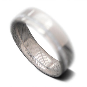 May include: A silver ring with a patterned design. The ring is made of metal and has a smooth, polished finish.