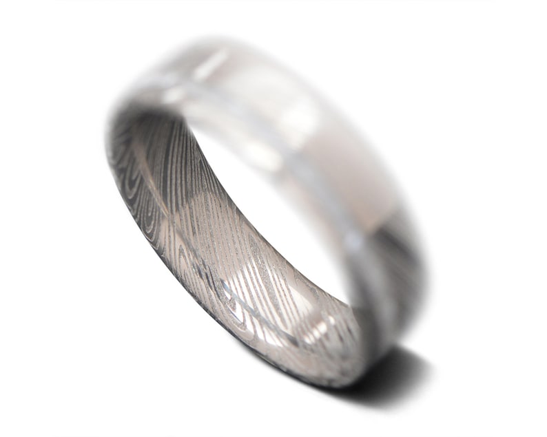 May include: A silver ring with a patterned design. The ring is made of metal and has a smooth, polished finish.