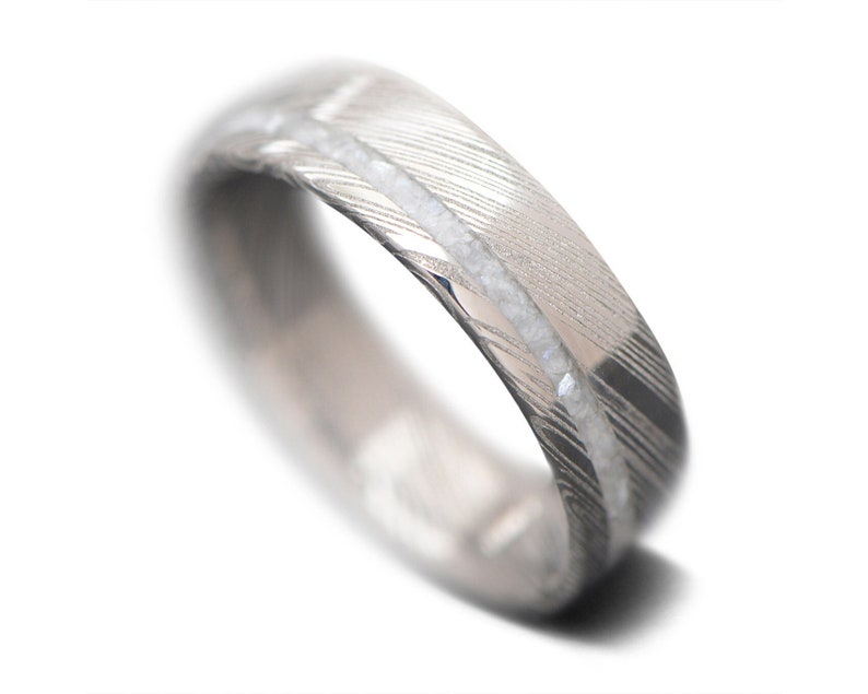 May include: A silver wedding band with a hammered finish and a row of small white diamonds.