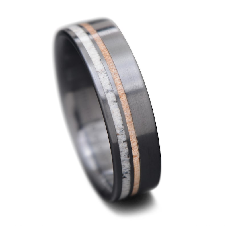 Black titanium wedding band with deer antler and birds eye maple inlays, 7mm mens ring, polished flat profile, free engraving option, displayed on a white background.