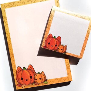 May include: Two blank notepads with fall-themed borders. The top notepad has a smaller notepad attached to it. Both notepads feature a cartoon pumpkin and cat design.