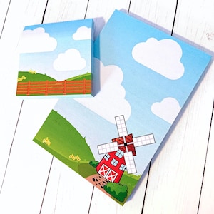 May include: Two blue and white patterned sticky note pads with a farm scene. One pad features a red barn with a windmill and the other pad features a wooden fence.