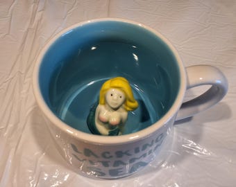 Lacking Vitamin Sea"  Ceramic Coffee Mug With Blonde Mermaid Inside, 12 oz, Whimsical Cupboard, 10 Strawberry St., Designed in the USA.