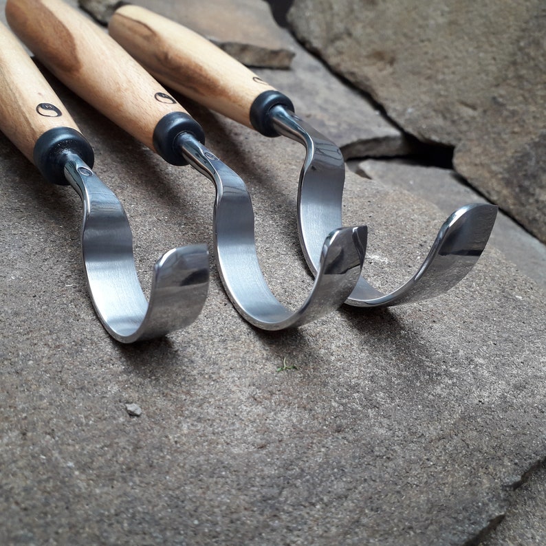 May include: Three wood carving tools with curved metal blades and wooden handles.