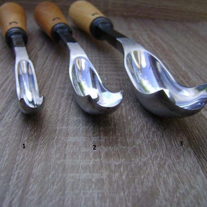 以下が含まれることがあります： 湾曲した刃と木製のハンドルが付いた木彫りの道具が3つあります。道具は1、2、3と番号が付けられています。