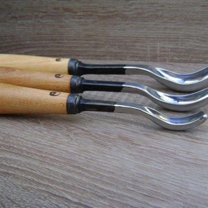 以下が含まれることがあります： 異なるサイズの湾曲した刃を持つ、木製のハンドルが付いた彫刻工具が3つあります。刃は1、2、3と番号が付けられています。