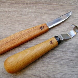 Op de afbeelding: Twee houtsnijgereedschappen met metalen bladen. Het gereedschap aan de linkerkant heeft een gebogen blad en het gereedschap aan de rechterkant heeft een haakvormig blad.