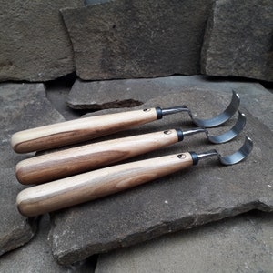 May include: Three wood carving tools with curved blades and wooden handles. The tools are arranged in a row, with the largest tool at the top and the smallest tool at the bottom.