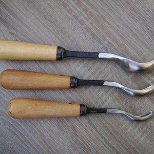 以下が含まれることがあります： 木製のハンドルと湾曲した金属製の刃を持つ木彫りの道具が3つあります。道具は1、2、3と番号が付けられています。