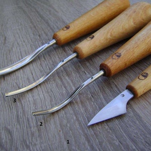 May include: Four wood carving tools with different shaped blades. The tools are numbered 1 through 4. The tools have wooden handles.