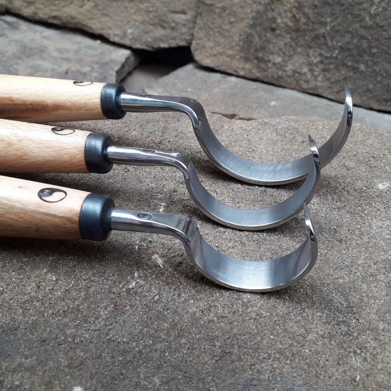 May include: Three wood carving tools with curved blades and wooden handles. The handles are marked with a yin yang symbol.