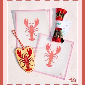 May include: Two square needlepoint canvases featuring a red lobster design, a heart-shaped finished needlepoint ornament with a red lobster, and a bundle of red and black embroidery floss with a Purl & Point label and two needles.