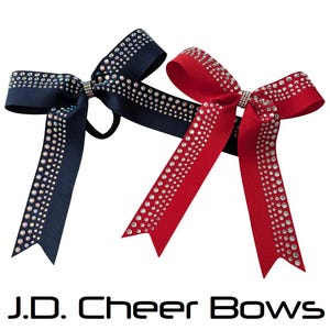 May include: Two cheer bows, one navy blue and one red, are displayed. Both bows are adorned with sparkling rhinestones. The text "J.D. Cheer Bows" is printed in black at the bottom of the image.