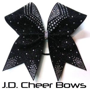 May include: Black cheer bow with silver glitter and rhinestones. The bow is tied with a black elastic band.