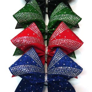 May include: Four cheer bows with rhinestones. The bows are black, green, red, and blue.