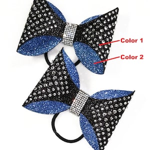 May include: Two black and blue cheer bows with rhinestones. The bows are tied together with a black elastic band. The bows are decorated with silver rhinestones. "J.D. Cheer Bows" is written at the bottom of the image.