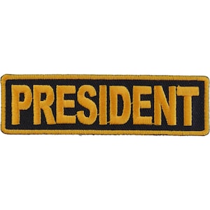 May include: A black and gold embroidered patch with the word "PRESIDENT" in yellow lettering.