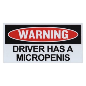 May include: A white warning sign with black text and a red oval with the word "WARNING" in white. The text on the sign reads "DRIVER HAS A MICROPENIS".
