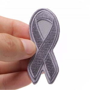 May include: A gray embroidered ribbon patch. The ribbon is tied in a bow shape.