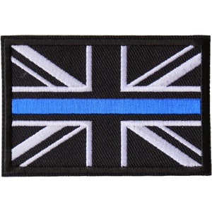 May include: A rectangular patch featuring the Union Jack flag in black, white, and blue. The design includes a blue stripe across the center, with white embroidered lines on a black background.