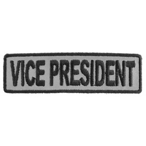 May include: A gray and black embroidered patch with the text "VICE PRESIDENT" in black.